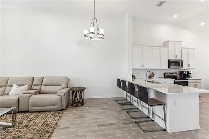 Kitchen with a breakfast bar area, appliances with stainless steel finishes, white cabinets, a peninsula, and open floor plan
