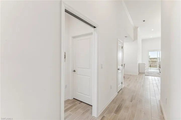 Corridor with wood finish floors and recessed lighting