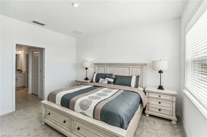 Bedroom featuring light carpet and ensuite bath