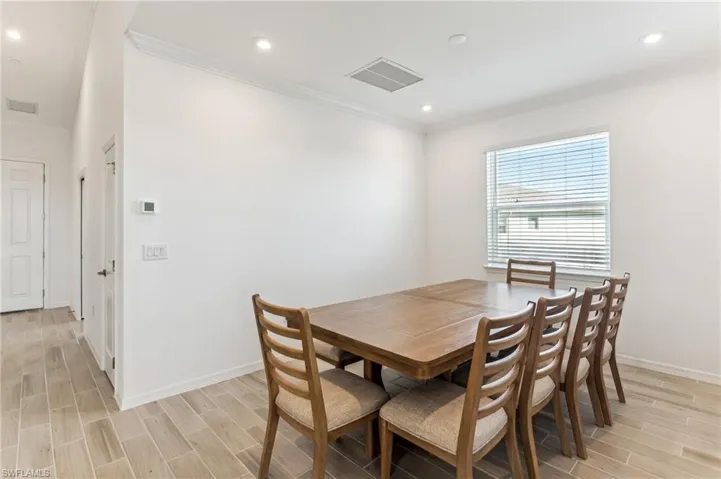 Dining space featuring wood tiled floors, ornamental molding, and recessed lighting