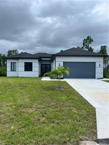 Single story home with a garage and a front lawn