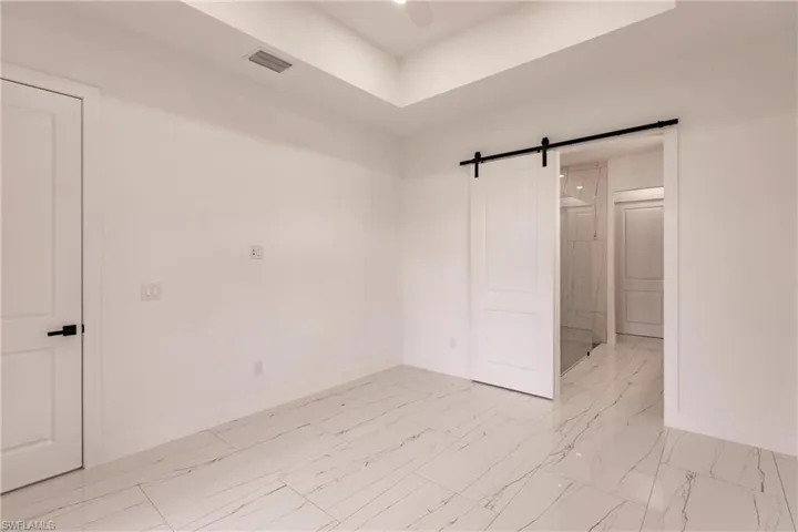Unfurnished bedroom featuring a barn door and light tile flooring