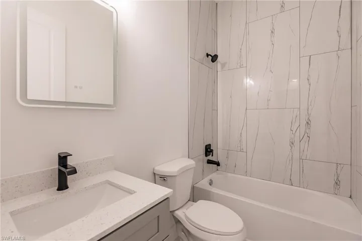 Full bathroom featuring tiled shower / bath, toilet, and vanity
