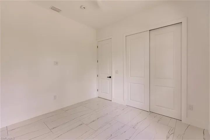 Unfurnished bedroom with a closet and light tile flooring