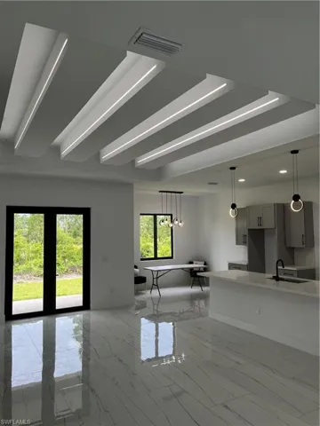 Unfurnished living room with sink, light tile patterned floors, and a raised ceiling