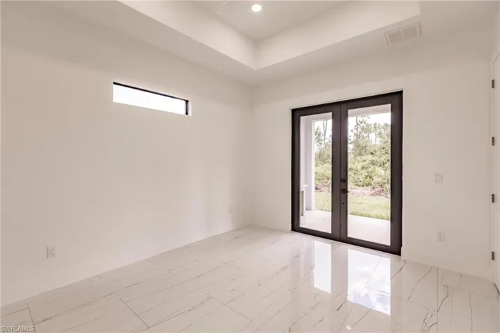 Tiled empty room featuring french doors