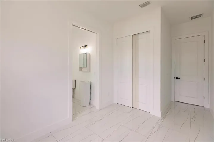 Unfurnished bedroom featuring a closet, light tile flooring, and connected bathroom