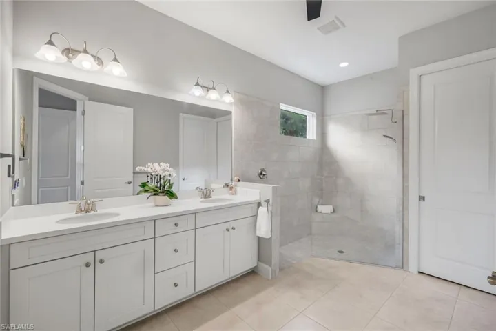 Full bath featuring double vanity, walk in shower, light tile patterned flooring, and recessed lighting