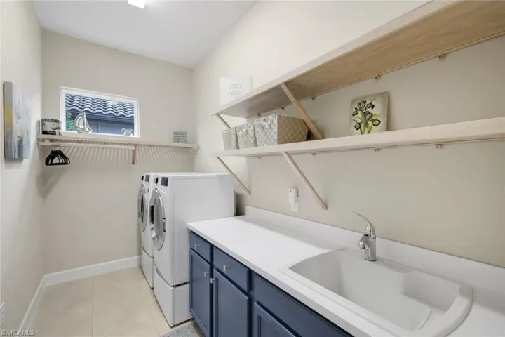 Laundry area with washer and dryer, light tile patterned floors, and cabinet space