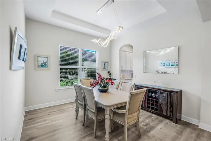 Dining area with a raised ceiling, light wood finished floors, and a chandelier