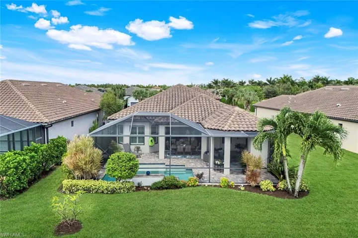 Rear view of house with an outdoor pool, a sunroom, glass enclosure, and a tiled roof