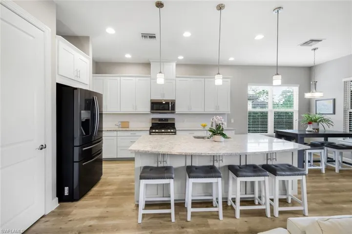 Kitchen with white cabinetry, appliances with stainless steel finishes, a breakfast bar, pendant lighting, and recessed lighting