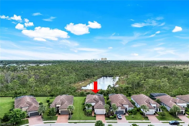 Aerial view of residential area featuring a nearby body of water and a tree filled landscape