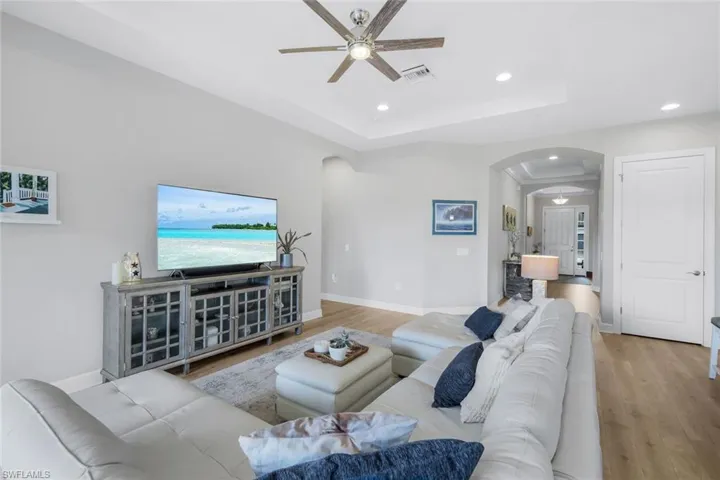 Large living area featuring a tray ceiling, a ceiling fan, recessed lighting