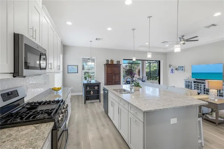 Kitchen with appliances with stainless steel finishes, white cabinetry, light wood-style flooring, light stone counters, and recessed lighting