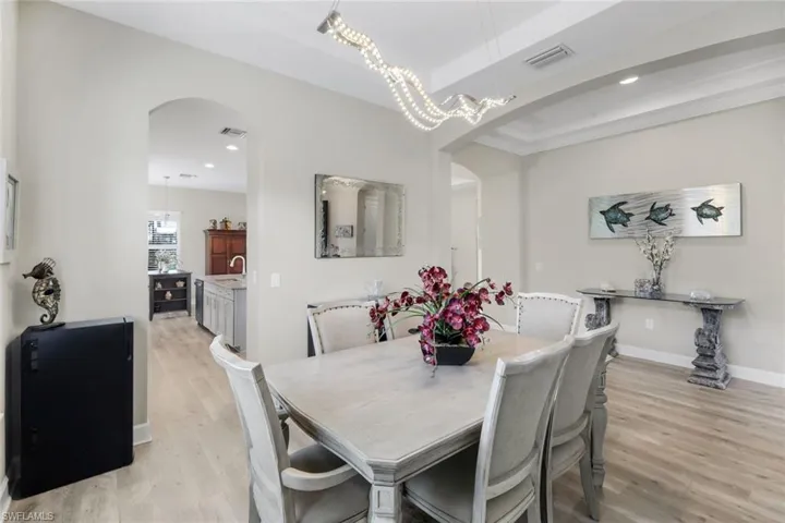 Dining space featuring arched walkways, light wood-style flooring, and recessed lighting