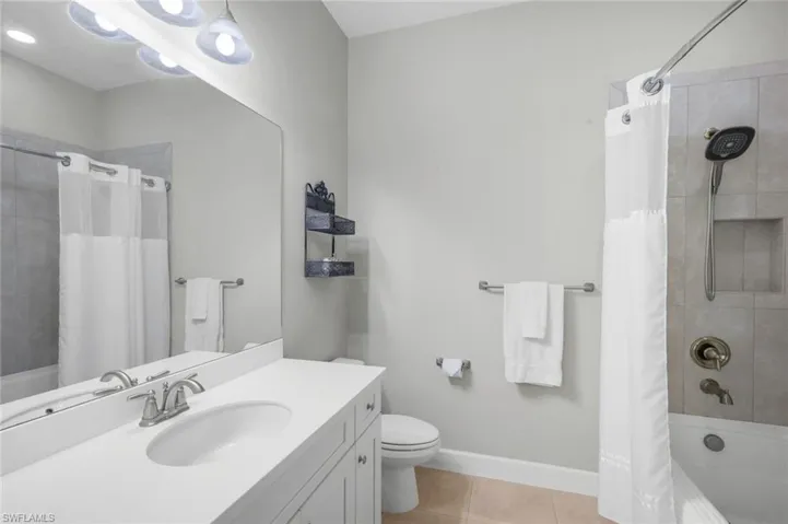 Full bath featuring shower / bath combo, light tile patterned floors, and vanity