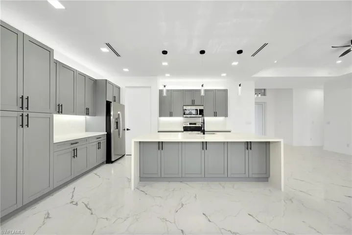 Kitchen featuring gray cabinets, stainless steel appliances, a kitchen island with sink, hanging light fixtures, and ceiling fan