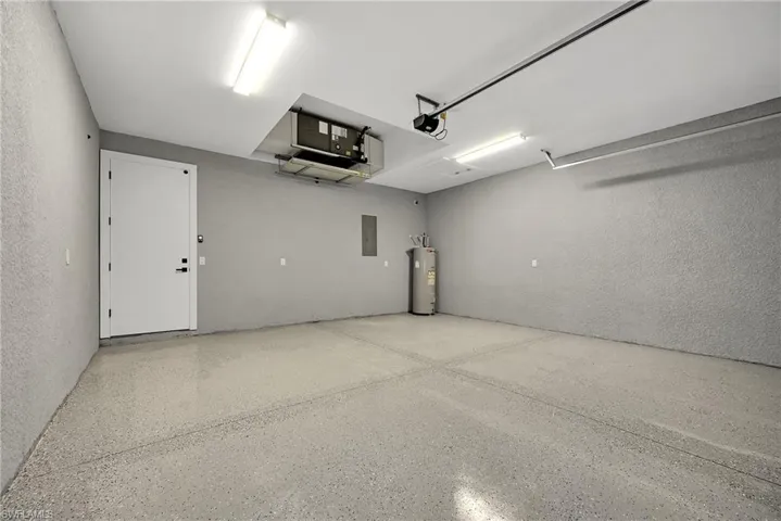 Garage featuring a garage door opener, gas water heater, and electric panel