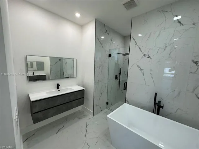 Bathroom with tile patterned floors, vanity, and separate shower and tub