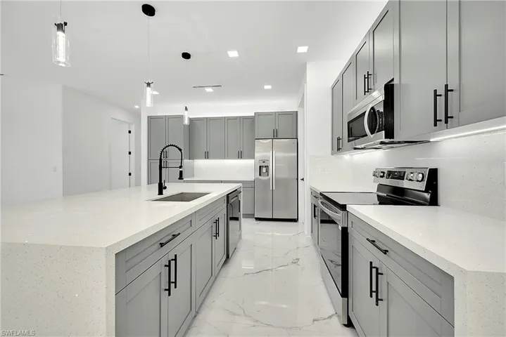 Kitchen featuring appliances with stainless steel finishes, sink, tasteful backsplash, light tile patterned flooring, and gray cabinetry