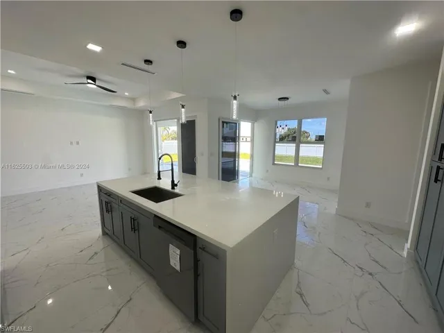 Kitchen with black dishwasher, ceiling fan, a kitchen island with sink, hanging light fixtures, and sink