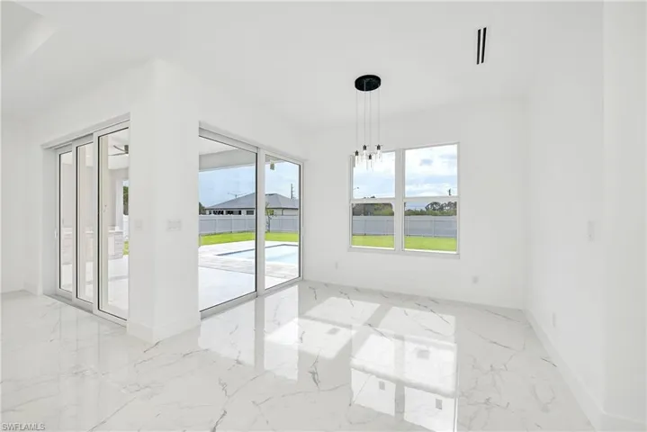Empty room featuring light tile patterned flooring and a chandelier
