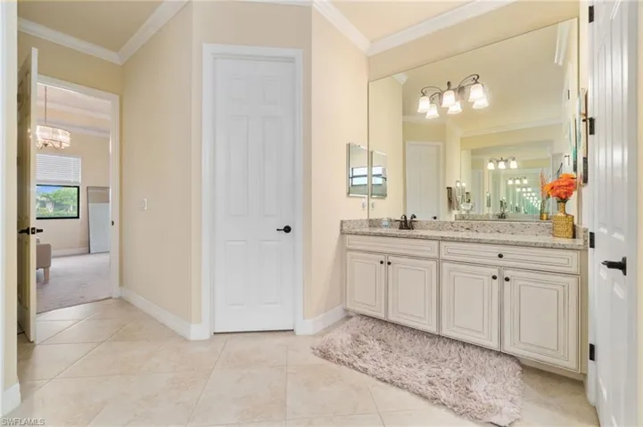 Dual sink vanity featuring a light-toned countertop, white cabinetry with black hardware, and an expansive mirror