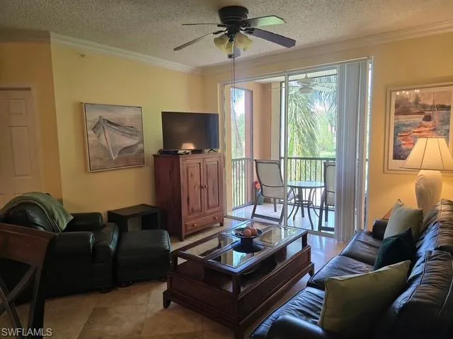 Living room featuring crown molding, a textured ceiling, and ceiling fan
