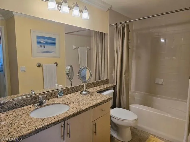 Bathroom featuring vanity, ornamental molding, shower / bathtub combination with curtain, and light tile patterned flooring