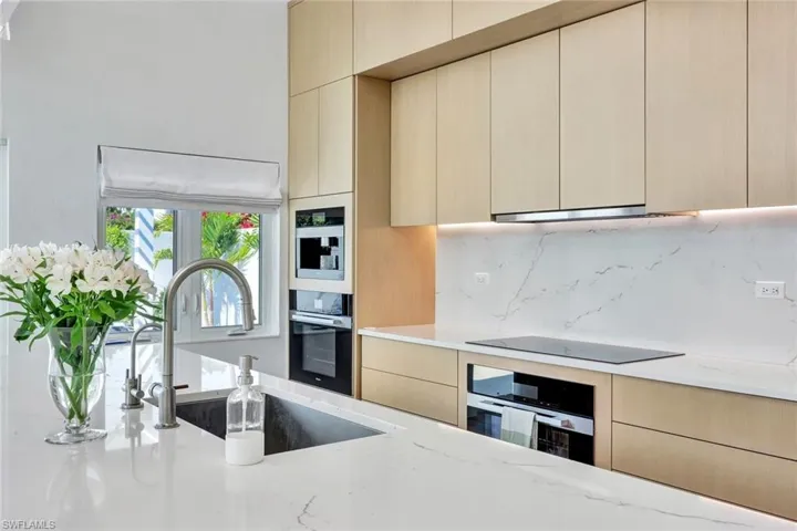 Kitchen featuring tasteful backsplash, black appliances, modern cabinets, and a sink
