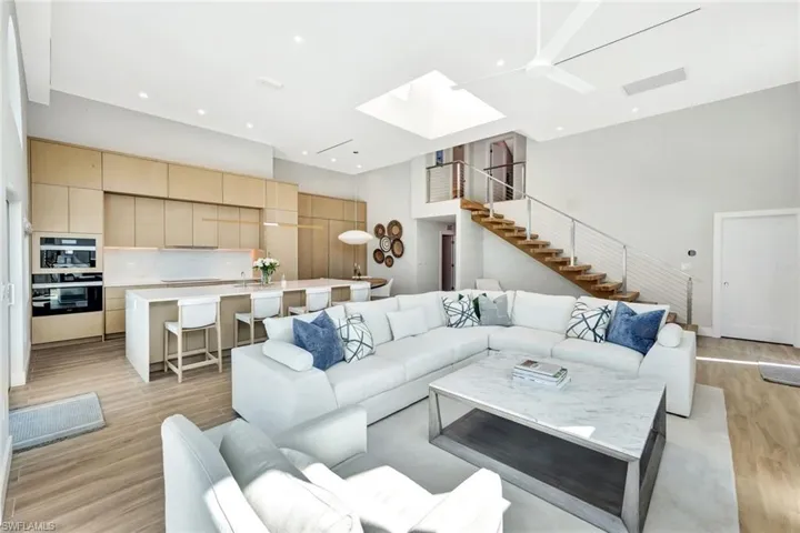 Living area featuring a skylight, stairway, a high ceiling, and light wood-style flooring