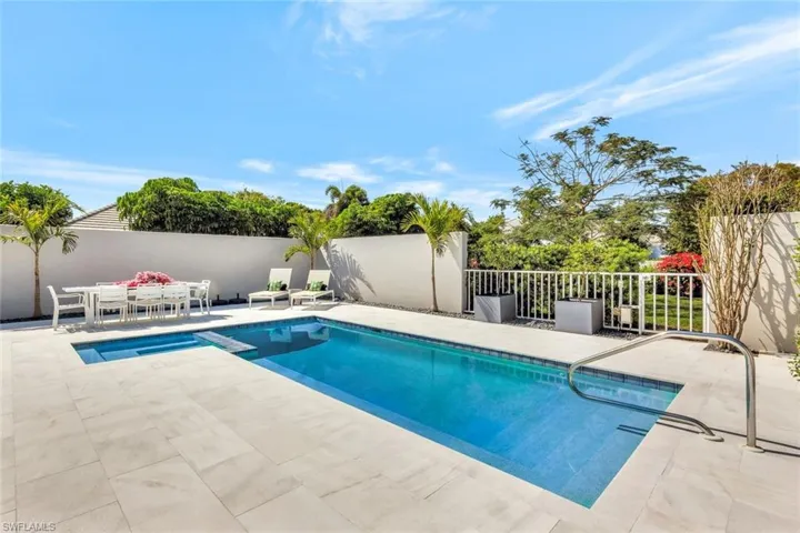 View of swimming pool with a patio, a pool with connected hot tub, and fence