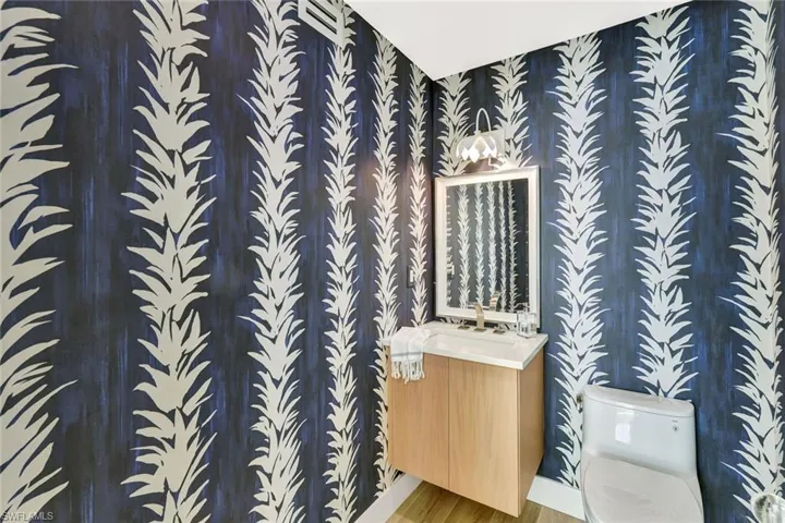 Half bath with vanity, toilet, and wood finished floors
