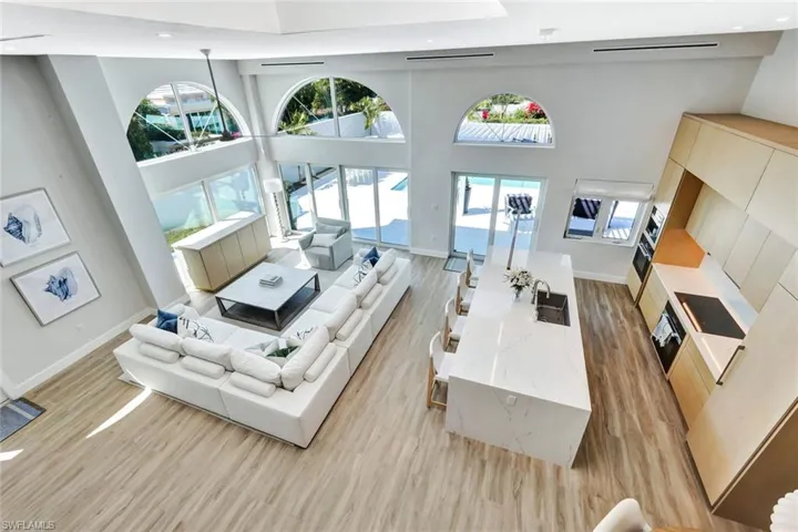 Living room featuring recessed lighting, baseboards, light wood-type flooring, and a towering ceiling