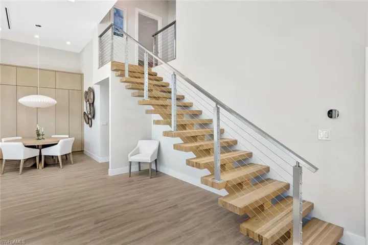 Stairway featuring a high ceiling, wood finished floors, and baseboards