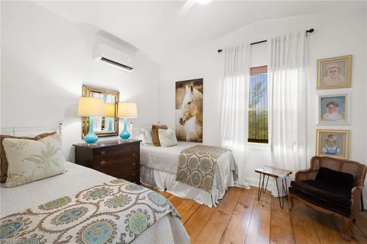 Bedroom featuring hardwood / wood-style floors, lofted ceiling, a ceiling fan, and a wall unit AC