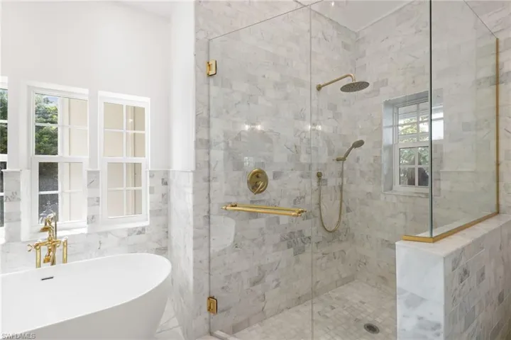 Bathroom with a soaking tub, a stall shower, tile walls, and a wainscoted wall