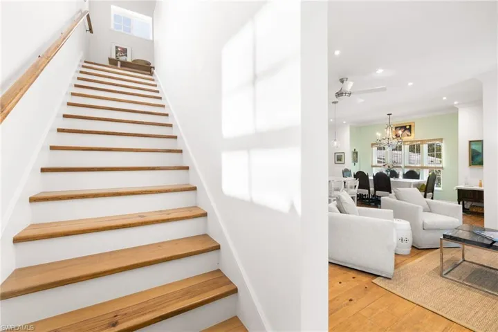 Stairs with hardwood / wood-style flooring, recessed lighting, a chandelier, ceiling fan, and ornamental molding