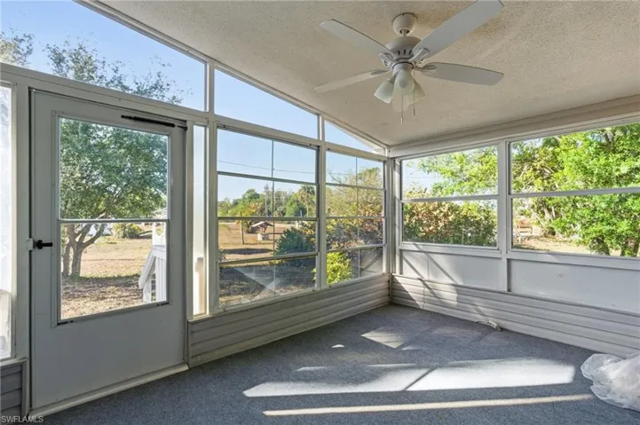 Unfurnished sunroom with ceiling fan, vaulted ceiling, and plenty of natural light