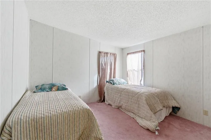 Carpeted bedroom featuring a textured ceiling and a decorative wall