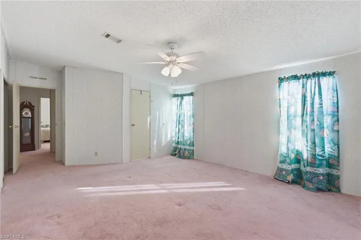 Unfurnished bedroom with carpet, a textured ceiling, and a ceiling fan