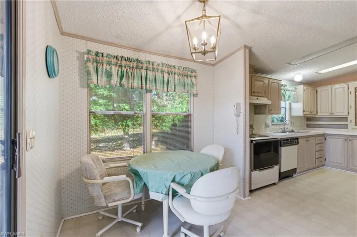 Dining space with wallpapered walls, light flooring, suspended lighting, and a textured ceiling