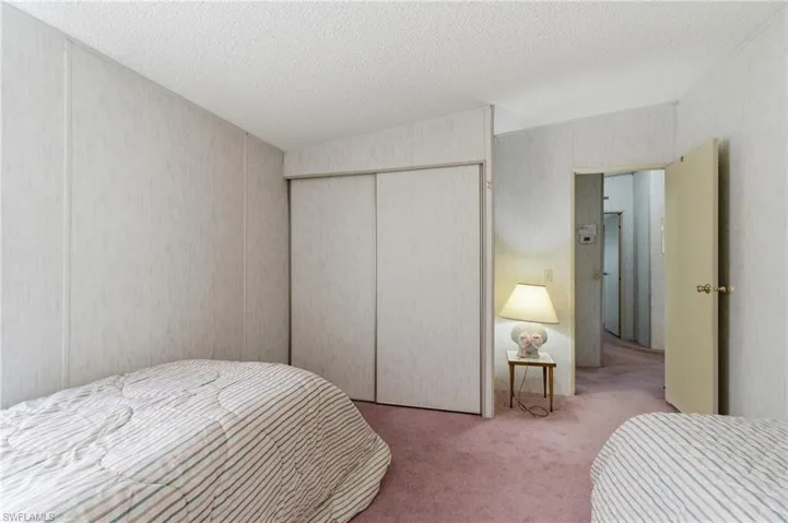 Bedroom with light carpet, a textured ceiling, and a closet