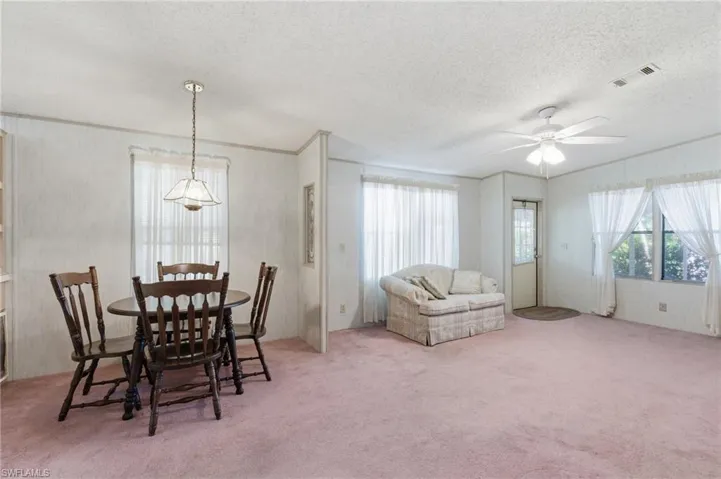 Dining room featuring light carpet, a textured ceiling, and a ceiling fan