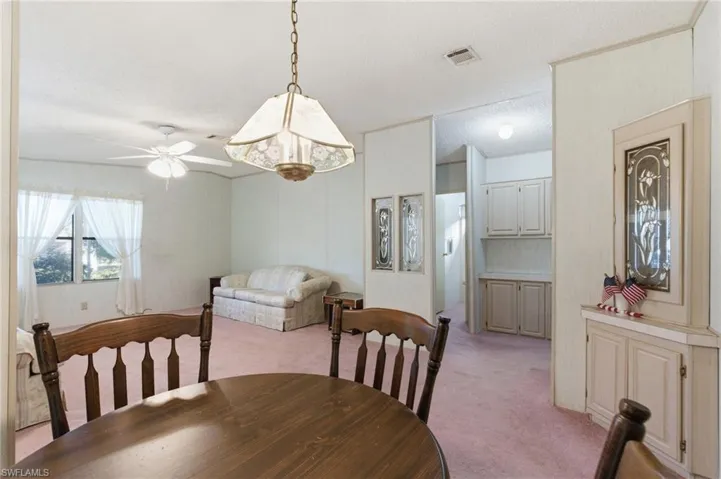 Dining space with light carpet, ceiling fan, and a textured ceiling