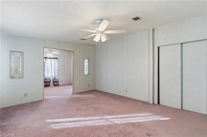 Carpeted spare room featuring a textured ceiling and a ceiling fan