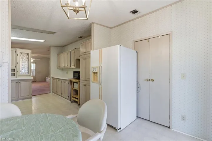 Dining room featuring light flooring, wallpapered walls, a textured ceiling, and a chandelier