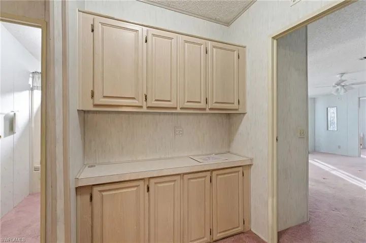 Bar with a textured ceiling, light countertops, light colored carpet, ceiling fan, and light wood finish cabinets