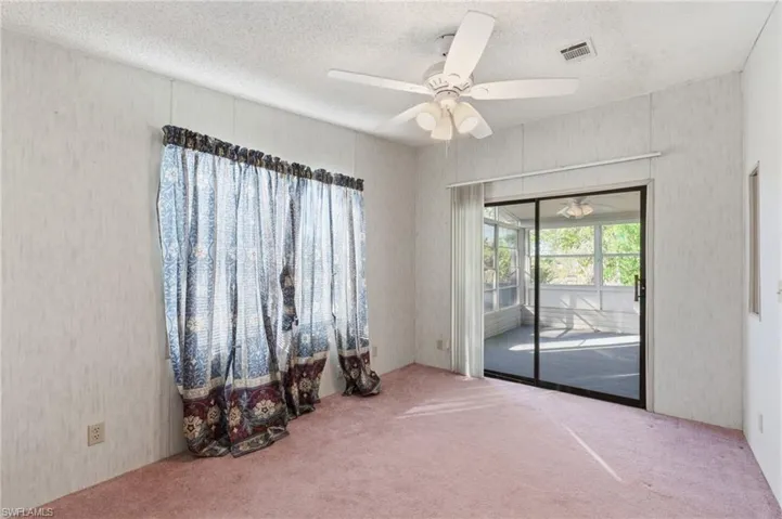 Spare room with a ceiling fan, a textured ceiling, and carpet